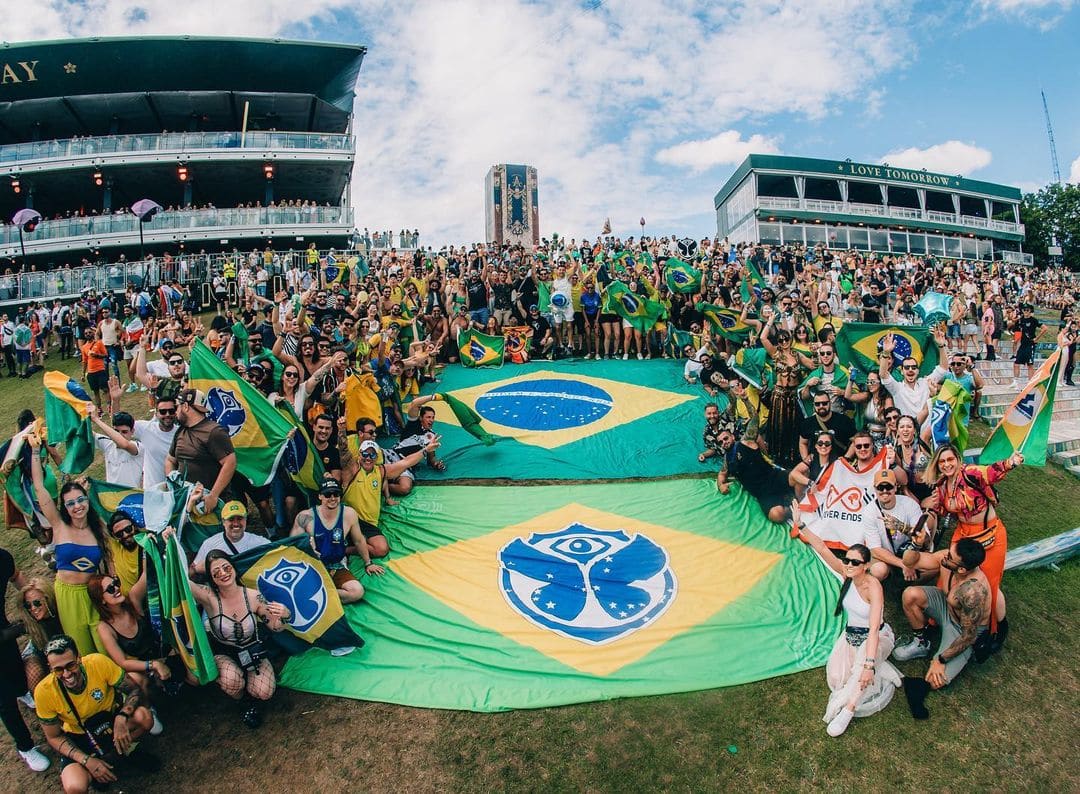 A família Never Ends com bandeiras gigantes do Brasil e da Tomorrowland abertas no gramado do festival
