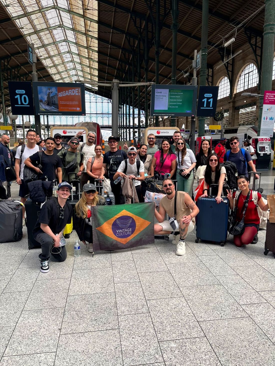 Grupo da Never Ends na plataforma do trem com destino a Amsterdam no painel