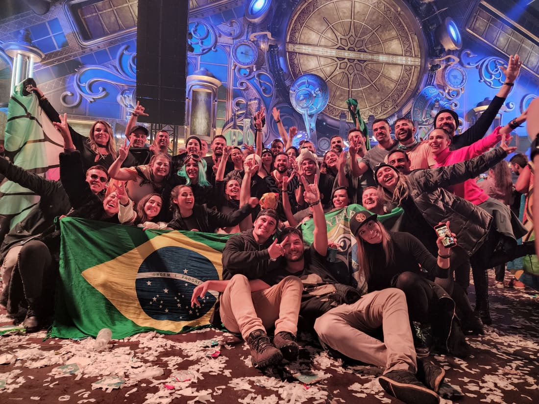 Grupo da Never Ends com a bandeira do Brasil dentro do Mainstage coberto da Tomorrowland Winter, com o chão tomado de papel picado no fim da noite