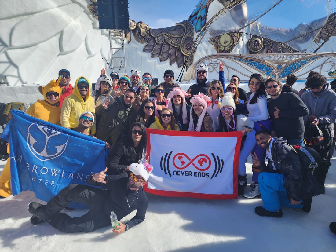 Grupo da Never Ends com a bandeira da agência e a bandeira da Tomorrowland Winter diante do palco esculpido em gelo, em Alpe d'Huez