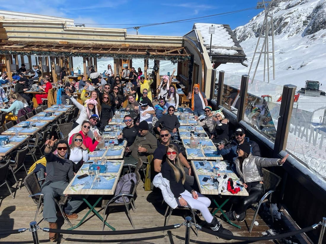 Grupo da Never Ends nas mesas compridas do terraço do restaurante Chantebise, na montanha de Alpe d'Huez