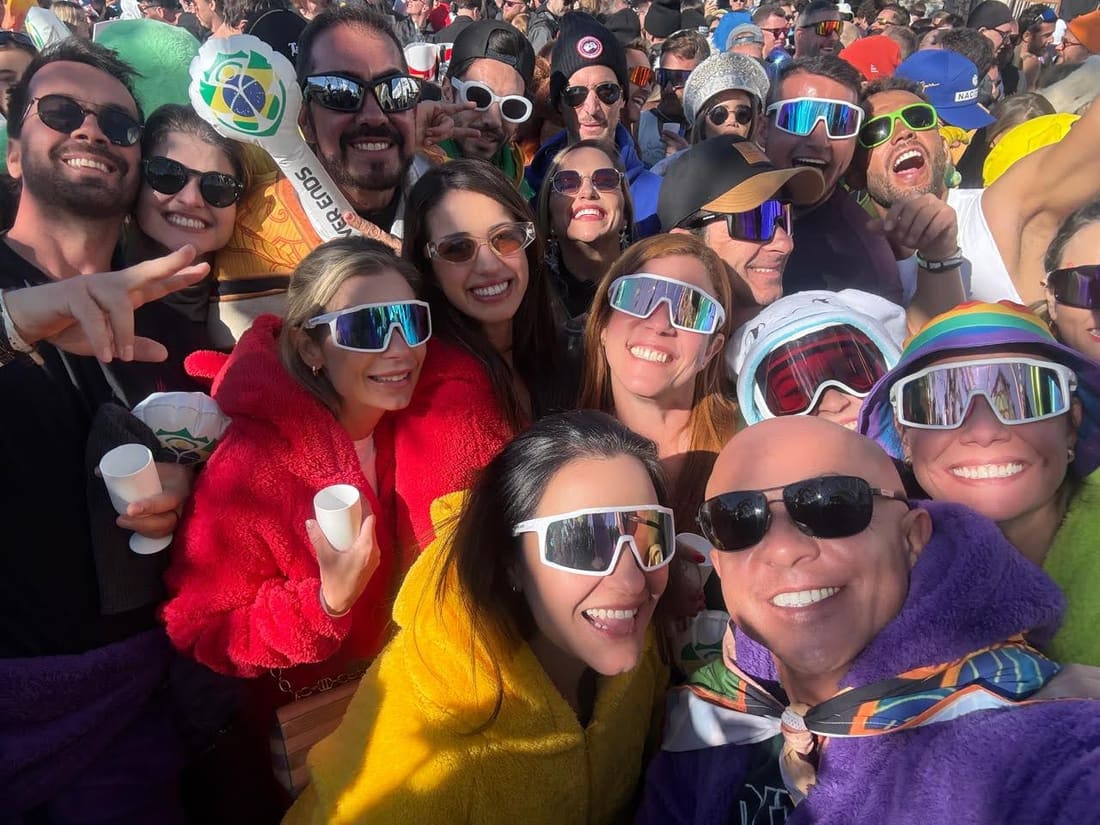 Viajantes da Never Ends no meio do público da Tomorrowland Winter, com a bandeira do Brasil da agência atrás