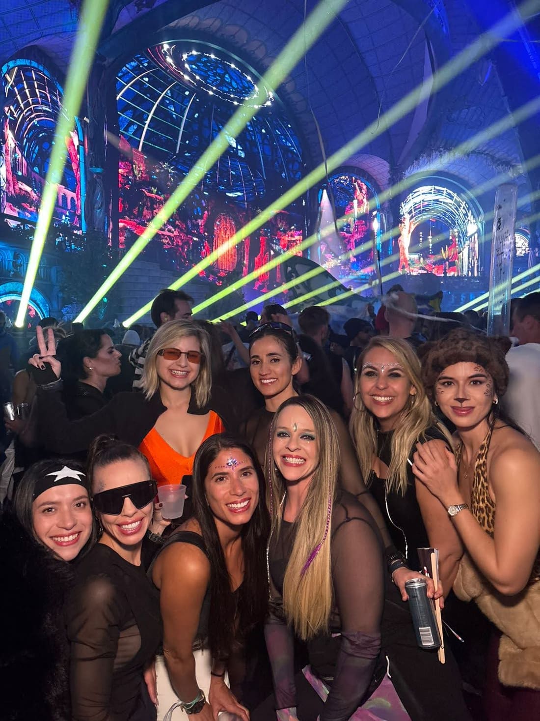 Viajantes da Never Ends no meio do público da Tomorrowland Winter, com os feixes de laser verdes cruzando o Mainstage coberto