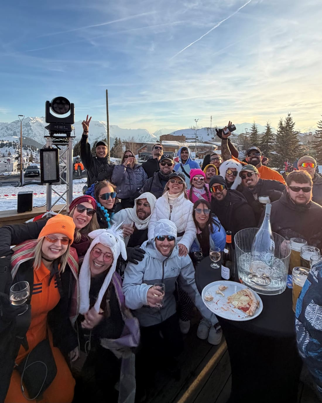 Grupo da Never Ends reunido em volta de uma mesa no fim de tarde em Alpe d'Huez, com os Alpes nevados atrás