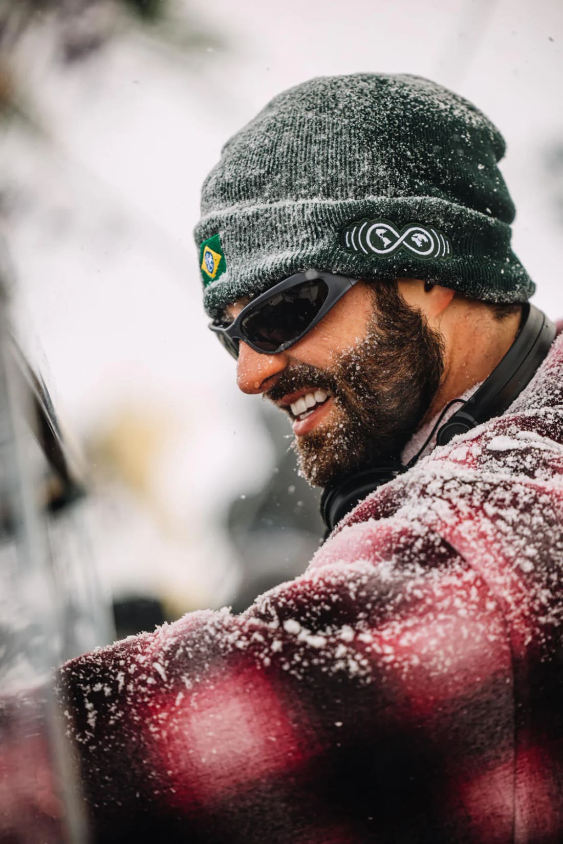 DJ com a touca da Never Ends coberta de neve, sorrindo atrás dos equipamentos na Tomorrowland Winter